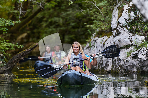 Image of A group of friends enjoying having fun and kayaking while exploring the calm river, surrounding forest and large natural river canyons