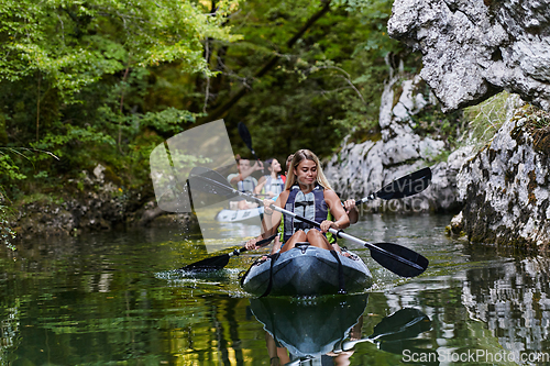 Image of A group of friends enjoying having fun and kayaking while exploring the calm river, surrounding forest and large natural river canyons