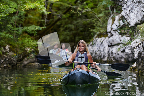 Image of A group of friends enjoying having fun and kayaking while exploring the calm river, surrounding forest and large natural river canyons