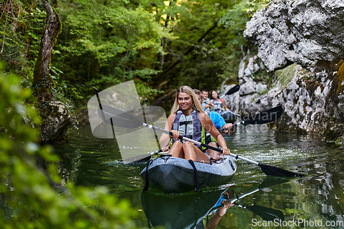 Image of A group of friends enjoying having fun and kayaking while exploring the calm river, surrounding forest and large natural river canyons