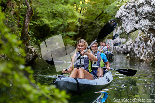 Image of A group of friends enjoying having fun and kayaking while exploring the calm river, surrounding forest and large natural river canyons