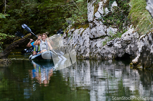 Image of A young couple enjoying an idyllic kayak ride in the middle of a beautiful river surrounded by forest greenery