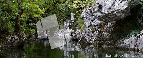 Image of A group of friends enjoying having fun and kayaking while exploring the calm river, surrounding forest and large natural river canyons