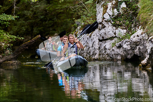 Image of A group of friends enjoying having fun and kayaking while exploring the calm river, surrounding forest and large natural river canyons