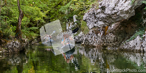 Image of A group of friends enjoying having fun and kayaking while exploring the calm river, surrounding forest and large natural river canyons