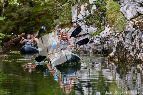 Image of A group of friends enjoying having fun and kayaking while exploring the calm river, surrounding forest and large natural river canyons