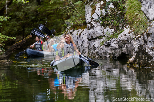 Image of A group of friends enjoying having fun and kayaking while exploring the calm river, surrounding forest and large natural river canyons