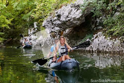 Image of A group of friends enjoying having fun and kayaking while exploring the calm river, surrounding forest and large natural river canyons