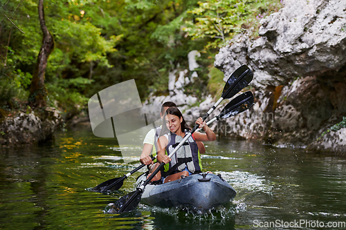 Image of A young couple enjoying an idyllic kayak ride in the middle of a beautiful river surrounded by forest greenery