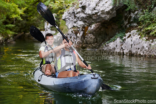 Image of A young couple enjoying an idyllic kayak ride in the middle of a beautiful river surrounded by forest greenery