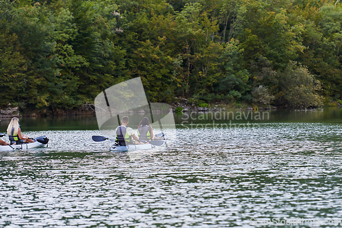 Image of A young couple enjoying an idyllic kayak ride in the middle of a beautiful river surrounded by forest greenery