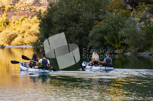 Image of A group of friends enjoying having fun and kayaking while exploring the calm river, surrounding forest and large natural river canyons