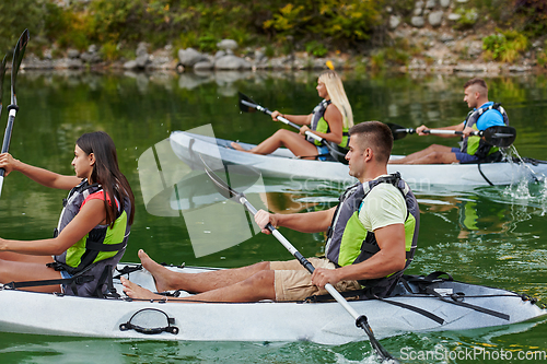 Image of A group of friends enjoying having fun and kayaking while exploring the calm river, surrounding forest and large natural river canyons