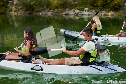 Image of A group of friends enjoying having fun and kayaking while exploring the calm river, surrounding forest and large natural river canyons