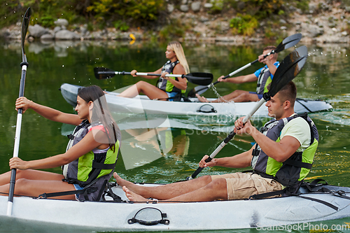 Image of A group of friends enjoying having fun and kayaking while exploring the calm river, surrounding forest and large natural river canyons