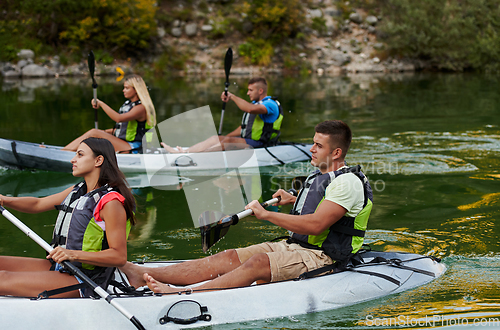 Image of A group of friends enjoying having fun and kayaking while exploring the calm river, surrounding forest and large natural river canyons