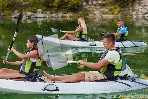 Image of A group of friends enjoying having fun and kayaking while exploring the calm river, surrounding forest and large natural river canyons