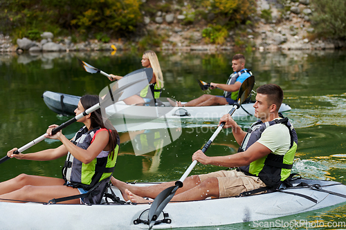 Image of A group of friends enjoying having fun and kayaking while exploring the calm river, surrounding forest and large natural river canyons