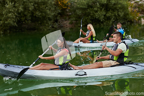 Image of A group of friends enjoying having fun and kayaking while exploring the calm river, surrounding forest and large natural river canyons