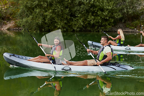 Image of A group of friends enjoying having fun and kayaking while exploring the calm river, surrounding forest and large natural river canyons