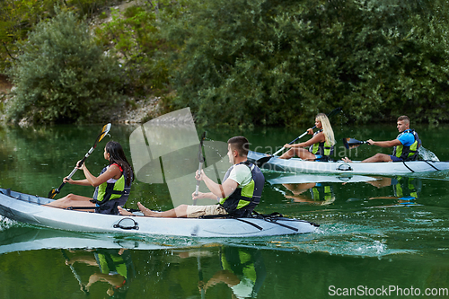 Image of A group of friends enjoying having fun and kayaking while exploring the calm river, surrounding forest and large natural river canyons