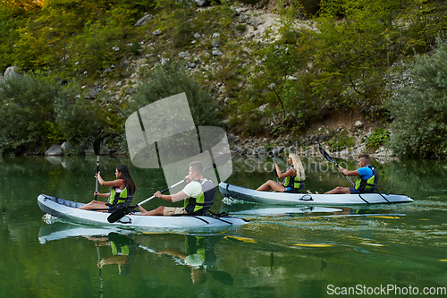 Image of A group of friends enjoying having fun and kayaking while exploring the calm river, surrounding forest and large natural river canyons