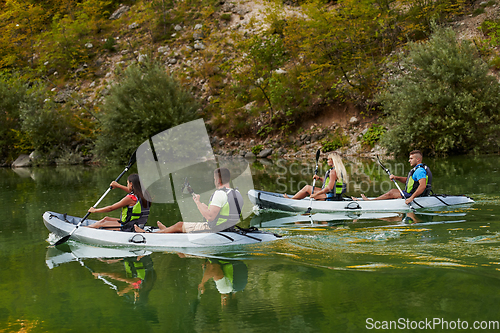 Image of A group of friends enjoying having fun and kayaking while exploring the calm river, surrounding forest and large natural river canyons