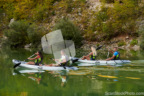 Image of A group of friends enjoying having fun and kayaking while exploring the calm river, surrounding forest and large natural river canyons