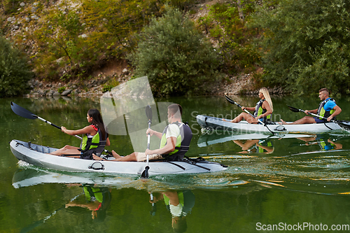 Image of A group of friends enjoying having fun and kayaking while exploring the calm river, surrounding forest and large natural river canyons