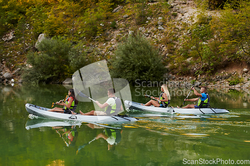 Image of A group of friends enjoying having fun and kayaking while exploring the calm river, surrounding forest and large natural river canyons