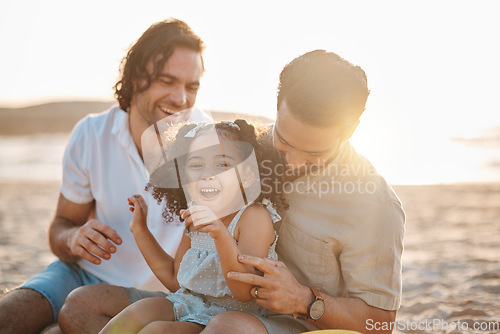 Image of Gay father, family and girl at beach with love, smile and hug for vacation, laugh and outdoor on sand in sunset. LGBTQ men, young kid and adoption with parents, holiday and comic tickling in summer