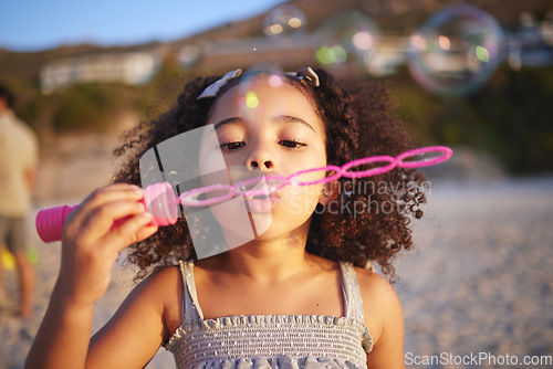 Image of Girl child, beach and blowing bubbles with playing, outdoor and freedom on sand, games and thinking in nature. Female kid, soap and water with plastic toys with wind, summer sunshine and vacation