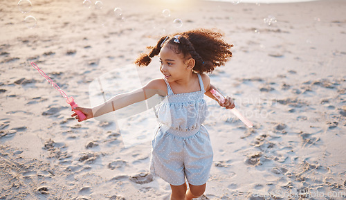 Image of Girl child, beach and outdoor with bubbles, playing and freedom on sand, games and smile in nature. Young female kid, soap and water with plastic toys in wind, summer sunshine and happy on vacation