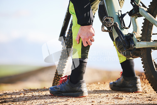 Image of Hand, cycling and leg pain with a person on a bike outdoor on a dirt track for fitness or exercise. Sports, training injury injury and an athlete on a bike with a medical emergency or accident