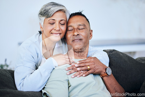 Image of Love, romance and a senior couple on a sofa in the living room of their home together during retirement. Happy, relax and hug with an elderly woman embracing her husband for comfort in a house
