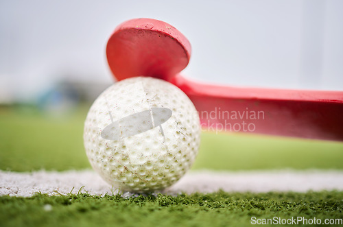 Image of Closeup, grass and a stick and ball for hockey, sports and training on a field for a game. Fitness, exercise and gear for a match, workout or competition on a turf or ground of a park for cardio