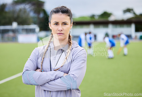 Image of Woman coach, arms crossed and field for sports, hockey and portrait for teaching, fitness and exercise. Girl, serious face and guide for development, leadership and training for competition on grass