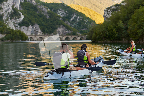 Image of A group of friends enjoying having fun and kayaking while exploring the calm river, surrounding forest and large natural river canyons