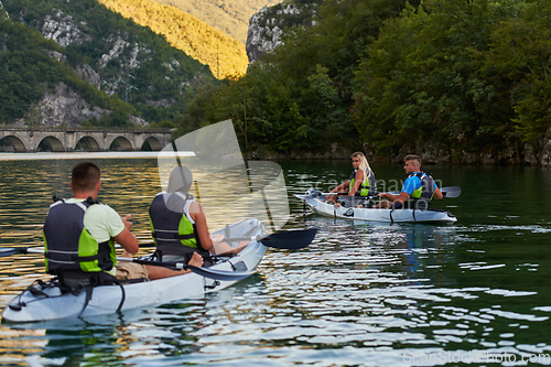 Image of A group of friends enjoying having fun and kayaking while exploring the calm river, surrounding forest and large natural river canyons