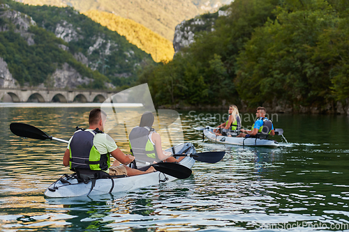 Image of A group of friends enjoying having fun and kayaking while exploring the calm river, surrounding forest and large natural river canyons