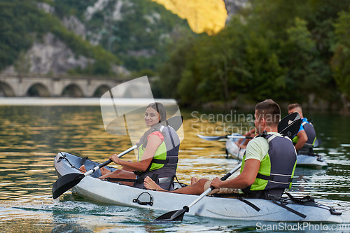 Image of A group of friends enjoying having fun and kayaking while exploring the calm river, surrounding forest and large natural river canyons