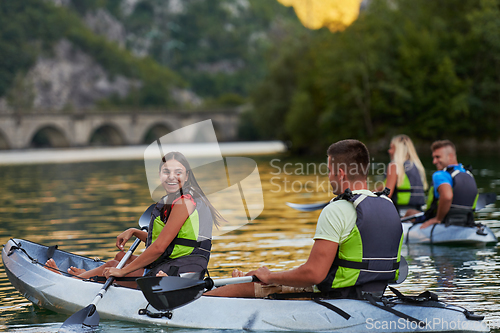 Image of A group of friends enjoying having fun and kayaking while exploring the calm river, surrounding forest and large natural river canyons