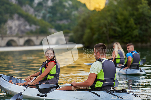 Image of A group of friends enjoying having fun and kayaking while exploring the calm river, surrounding forest and large natural river canyons