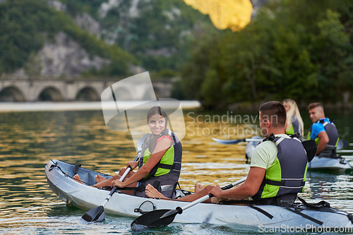 Image of A group of friends enjoying having fun and kayaking while exploring the calm river, surrounding forest and large natural river canyons