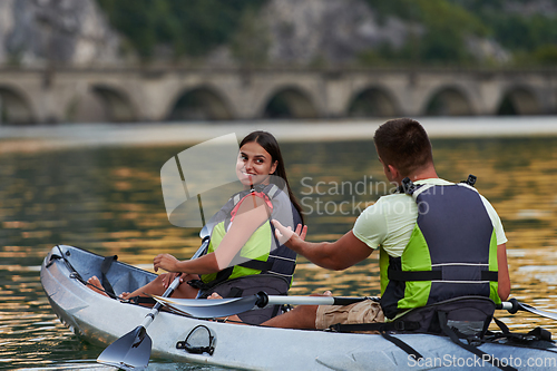 Image of A young couple enjoying an idyllic kayak ride in the middle of a beautiful river surrounded by forest greenery