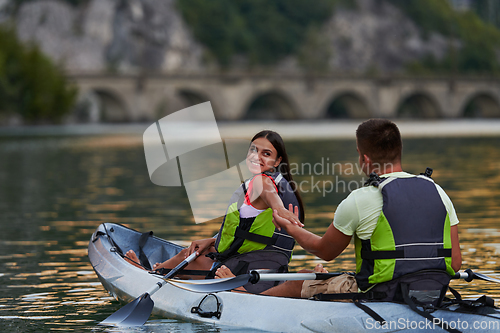 Image of A young couple enjoying an idyllic kayak ride in the middle of a beautiful river surrounded by forest greenery