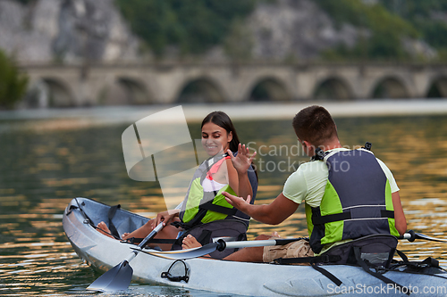 Image of A young couple enjoying an idyllic kayak ride in the middle of a beautiful river surrounded by forest greenery