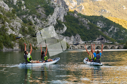 Image of A group of friends enjoying having fun and kayaking while exploring the calm river, surrounding forest and large natural river canyons