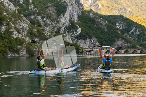 Image of A group of friends enjoying having fun and kayaking while exploring the calm river, surrounding forest and large natural river canyons