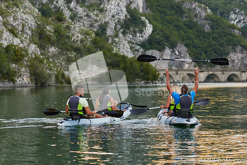 Image of A group of friends enjoying having fun and kayaking while exploring the calm river, surrounding forest and large natural river canyons